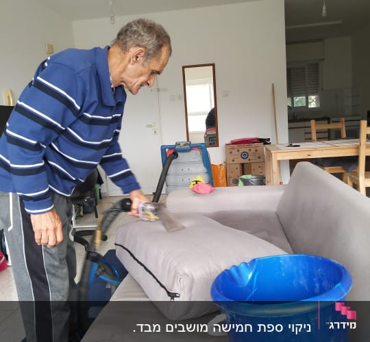אדם מנקה ספה עם שואב אבק ודלי כחול
